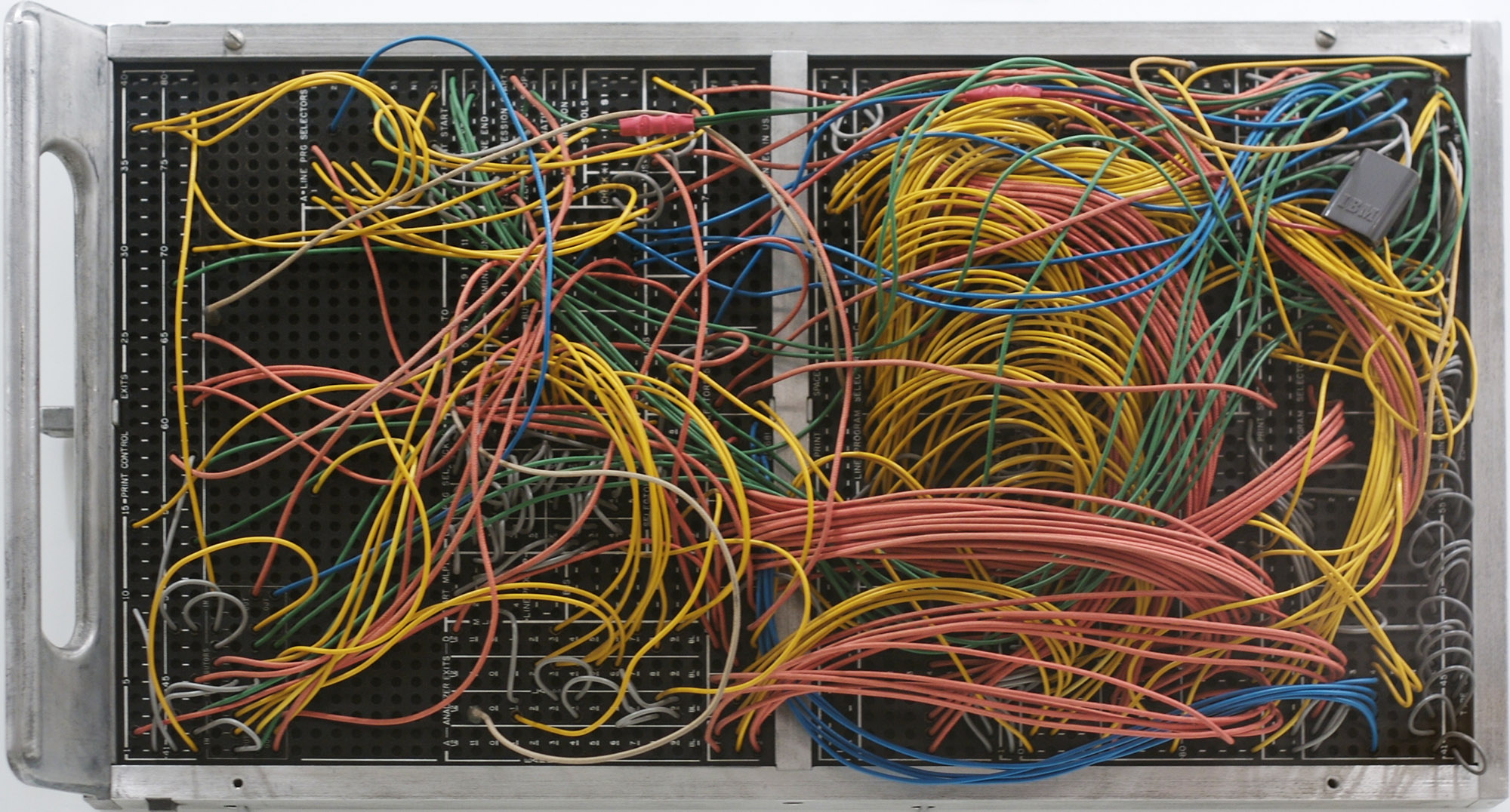 A black plug board in an aluminum frame with many various colored wires plugged into it.