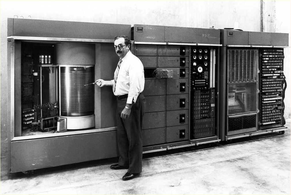 A series of three computer cabinets, approximately 7 feet tall by 30 feet long overall.
                             A man is standing in front of the disk storage unit.