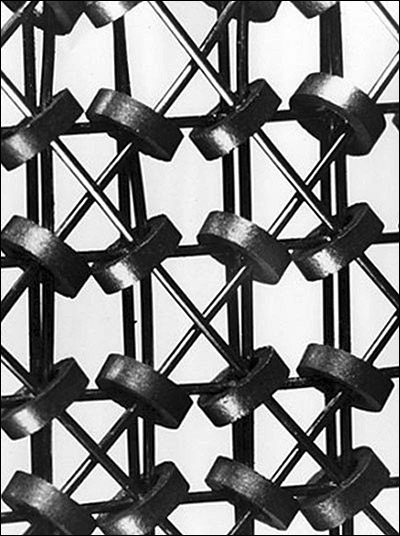 A lattice of small interlaced wires running through small round metal donuts.